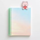 Spiralblock mit Farbverlauf in Blau und Rosa. Oben ein Clip in Form eines lachenden Schweinchens mit Herz.