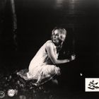 "In Flieger der Lust" in geschnörkelter Schrift. Eine Frau in einem weißen Kleid kniet im Wald auf Laub.