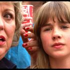 Ich kann keine Personen beschreiben. Eine ältere Frau und ein Kind schauen in dieselbe Richtung. Im Hintergrund ein roter Becher.