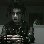 PLAY-Button oben rechts, Batterieladestand oben links. Person in dunkler, gothischer Kleidung sitzt vor einer Kamera.