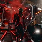 Ein futuristischer Raum mit leuchtend roten Akzenten. Eine Person in schwarzer Rüstung steht vor einer geöffneten, roten Kabine.