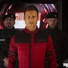 "RICHARDS" steht auf dem roten Anzug des Mannes, begleitet von zwei Wachen in Schwarz mit ernsten Minen.