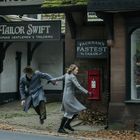 „Tailor Swift Bespoke Gentlemen's Tailoring“ und „Fackham's Fastest Tailor“ auf Schildern. Zwei Personen rennen.