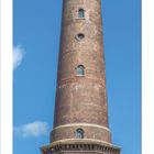 05 Kalender mit Monatsübersicht und rot markierten Wochenenden. Ziegel-Leuchtturm vor blauem Himmel auf einer Wiese.