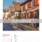 Vorjahresabbildung. März/April. Fachwerkhäuser mit roten Fensterläden und Kopfsteinpflaster in sonnigem Licht.