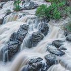 Kalender für Oktober. Wasserfall in üppiger Natur, Sonnenuntergang im Hintergrund, lebendige Vegetation.