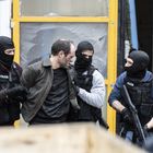 Mehrere maskierte Personen mit "Policia"-Westen halten einen Mann fest.