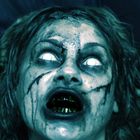 Keine erkennbaren Texte. Ein Gesicht mit gruselndem Ausdruck, blassen Augen und dunklen, fleckigen Zähnen.