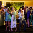 Mehrere fröhliche Erwachsene tanzen bei einer ausgelassenen Party in eleganter Kleidung.