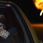 Text: "RabbitEars". Person fährt konzentriert Auto, nächtliche Szene, im Hintergrund Explosion.