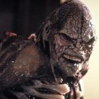 Ein groteskes, verzerrtes Gesicht mit welliger, fleckiger Haut zeigt eine finstere Grimasse.