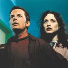 Zwei Menschen schauen überrascht und angespannt in dieselbe Richtung, ein Mann im Vordergrund, eine Frau dahinter.