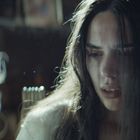 Es sind keine Texte im Bild vorhanden. Eine Frau mit langen, dunklen Haaren schaut nachdenklich in eine Richtung.