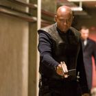 Ein Mann in taktischer Ausrüstung zielt mit einer Pistole in einem industriellen Korridor.