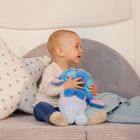 Ein kleines Kind sitzt auf einem Sofa, hält ein blaues Stofftier und ist von einem sternförmigen Kissen umgeben.