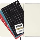 Sticker mit "2027", Buchstaben auf schwarzem, blauem und rotem Hintergrund, Notizbuch offen rechts.