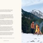 Text: "Snow Fire, Catalan Pyrenees..." Ein Mensch steht neben einem Lagerfeuer im Schnee, umgeben von Bergen und Wald.