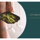 „UP FIRST“, „LITTLE PLATES, BIG CRAVEABILITY“, „24“. Person hält Teller mit grünem Gemüse und zwei leeren Gläsern.