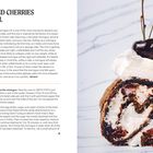 Titel: Chocolate and Cherries Meringue Roll. Rezeptbeschreibung für eine Baiserrolle. Foto zeigt die fertige Rolle mit Kirsche obendrauf.