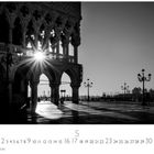 Der Text "Piazzetta San Marco". Schwarz-weiß, Sonne strahlt durch gotische Bögen auf einen gepflasterten Platz mit Laternen.