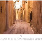 "Mdina" oben links, darunter Zahlen 1-31 in einer Reihe. Darstellung einer engen, gepflasterten Altstadtgasse mit warmem Licht.