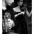 Mai-Kalender mit Musikern: eine Frau spielt Geige, daneben ein unscharfer Musiker. Schwarz-weiße Fotografie.