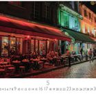 Das Bild zeigt ein belebtes Straßencafé bei Nacht in Montmartre mit roten Markisen und Menschen, die draußen sitzen.