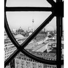 Kalenderblatt mit Monatsübersicht. Stadtansicht durch ein Fensterkreuz: Gebäude und Fernsehturm sichtbar.