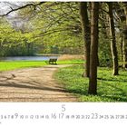 Kalenderblatt mit Mai-Daten. Abgebildet ist ein Waldweg mit Bank, umgeben von grünen Bäumen und einem See im Hintergrund.