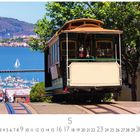 „Hyde Street Cable Car“. Ein Kabelwagen fährt eine Straße hinunter, mit Blick auf Wasser, Boote, eine Insel und Hügel.