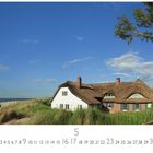 Ahrenshoop Grenzhaus. Unten Kalender mit Monatszahl 5. Haus mit Reetdach am Strand, blauer Himmel, Baum rechts.