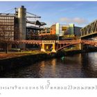 Beschriftung: "Technikmuseum", "ANHALT", "BVG". Eine Brücke über einem Fluss, Zug auf einer anderen Brücke, Gebäude im Hintergrund.