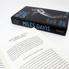 "MILES AHEAD – SOLIST IM GROSSENSEMBLE." Ein geöffnetes Buch und ein Hardcover über Miles Davis liegen auf einem Tisch.