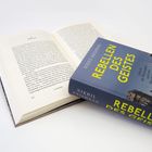 „REBELLEN DES GEISTES“, Nikhil Krishnan. Ein Buch mit blauem Einband liegt auf einem geöffneten Buch.