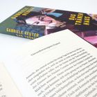 Text: "Gabriele Reuter, Das Tränenhaus" und "Vierundzwanzigstes Kapitel". Ein Buch liegt offen, ein anderes geschlossen daneben.