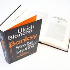 „Ulrich Blanché, Banksy: Straße und Mythos, Eine Biografie“. Zwei Bücher, eins geschlossen, eins geöffnet.