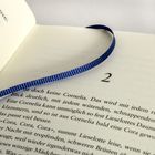 Aufgeschlagenes Buch, Textbeginn mit "2", blauer Stoffstreifen als Lesezeichen auf der Seite.
