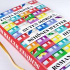 Texte: „TANJA KOKOSKA“, „GUTEN MORGEN, SCHÖNES WETTER“, „ROMAN“. 
Bunte Häuser und Regenschirme als Hintergrund.