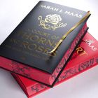 Zwei Bücher übereinander, oben: "SARAH J. MAAS", "A COURT OF THORNS AND ROSES", "DAS REICH DER SIEBEN HÖFE", mit goldener Rose.