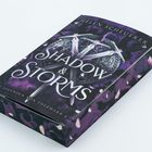 "SHADOW & STORMS" steht in großen weißen Buchstaben. Lila und schwarze Details mit Schwertern und einem stilisierten Schild.