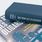Buch "Der Sohn des Oligarchen" von Patrick Radden Keefe; weiteres Buch mit Hochhausbild im Hintergrund.
