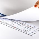Ein Kalenderblatt wird umgeblättert. Die Tage 14 bis 30 sind zu sehen, darunter Symbole für Wetter und Feiertage.