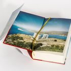 Ein aufgeschlagenes Buch mit einem Landschaftsfoto von Küste und Ruinen. Texte links auf aufgeschlagener Seite.