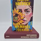 "Judith Hoersch, Niemands Töchter. Roman. Illustration: Frau mit Sonnenblume. Zwei Bücher, eines stehend, eines liegend."