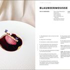 Text links: Blaubeermousse für 10 Personen.  
Rechts: Zutaten und detaillierte Anleitung. Teller mit Mousse in roter Sauce, dekoriert mit Blüten.