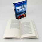 Der Text auf dem Buchcover lautet: "Tödlicher Hafen - Kokain Küste" von "Gerold Hänel". Das Buch liegt offen, Seiten 158-159.