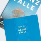 Zwei Buchumschläge in Blau. Text auf dem vorderen: "Walter Mayr GRENZFÄLLE". Hintergrund unscharf.
