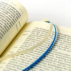 Ein aufgeschlagenes Buch mit hebräischen Begriffen: "Adonaj", "mircha", "kadosch". Ein blauer und beiger Stofffaden als Lesezeichen.