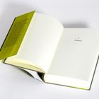 Auf der rechten Seite steht: "I. Trinken". Ein Buch mit gelbem Einband und offenem Deckel ist zu sehen.