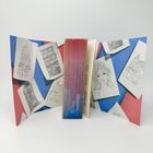 Seiten eines Buches, bedruckt mit Skizzen von Gebäuden und einem Porträt, auf rot-blauem Hintergrund arrangiert.